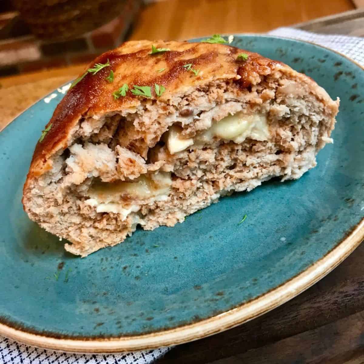 Cheese stuffed turkey meat loaf on a blue plate.