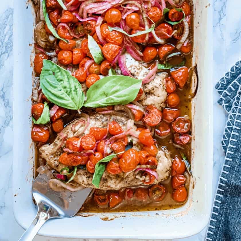 Brushetta baked chicken with tomatoes and basil in a baking dish.