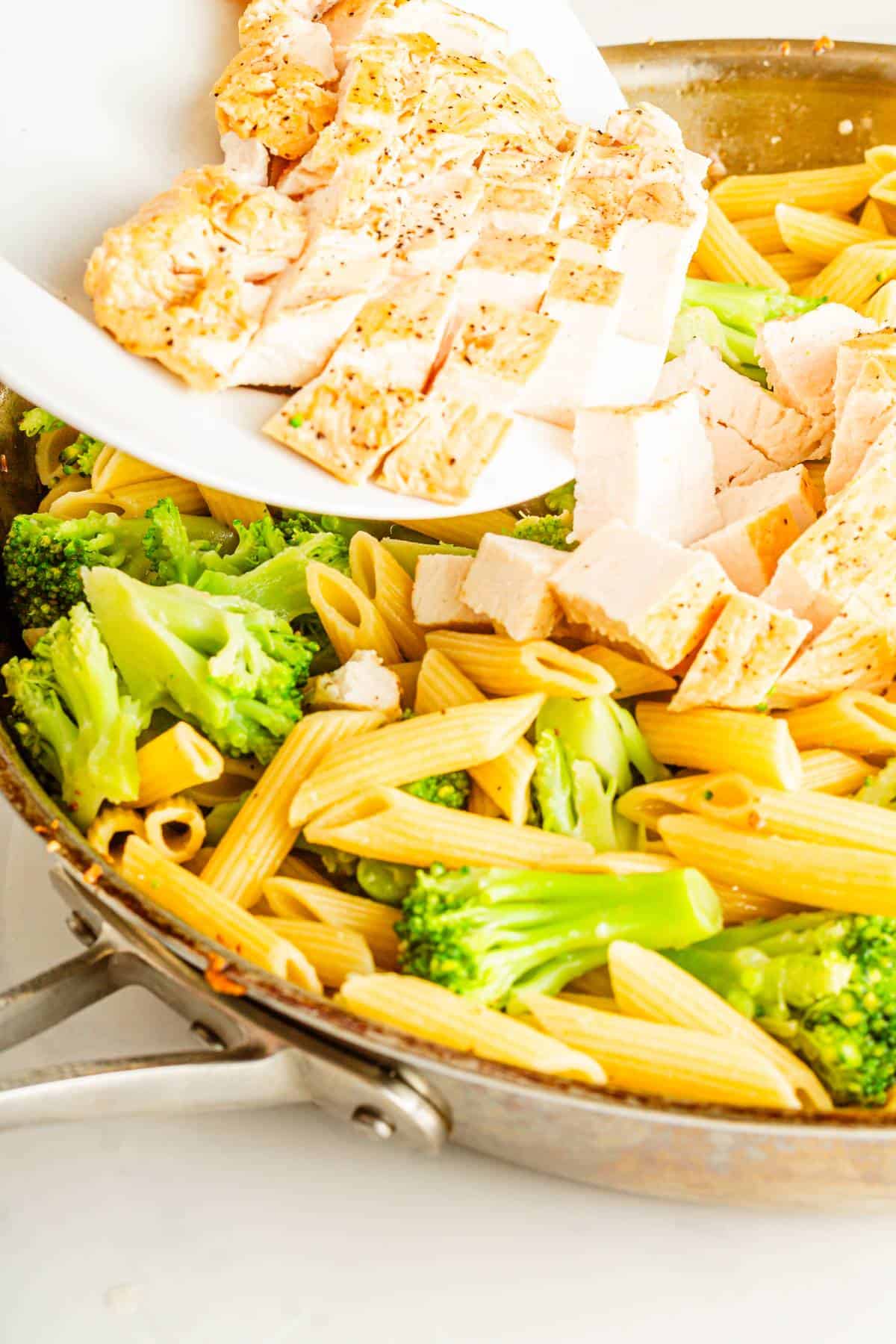 A pan of penne pasta with chicken and broccoli.