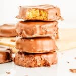 A stack of protein peanut butter cups covered in chocolate on a cutting board.