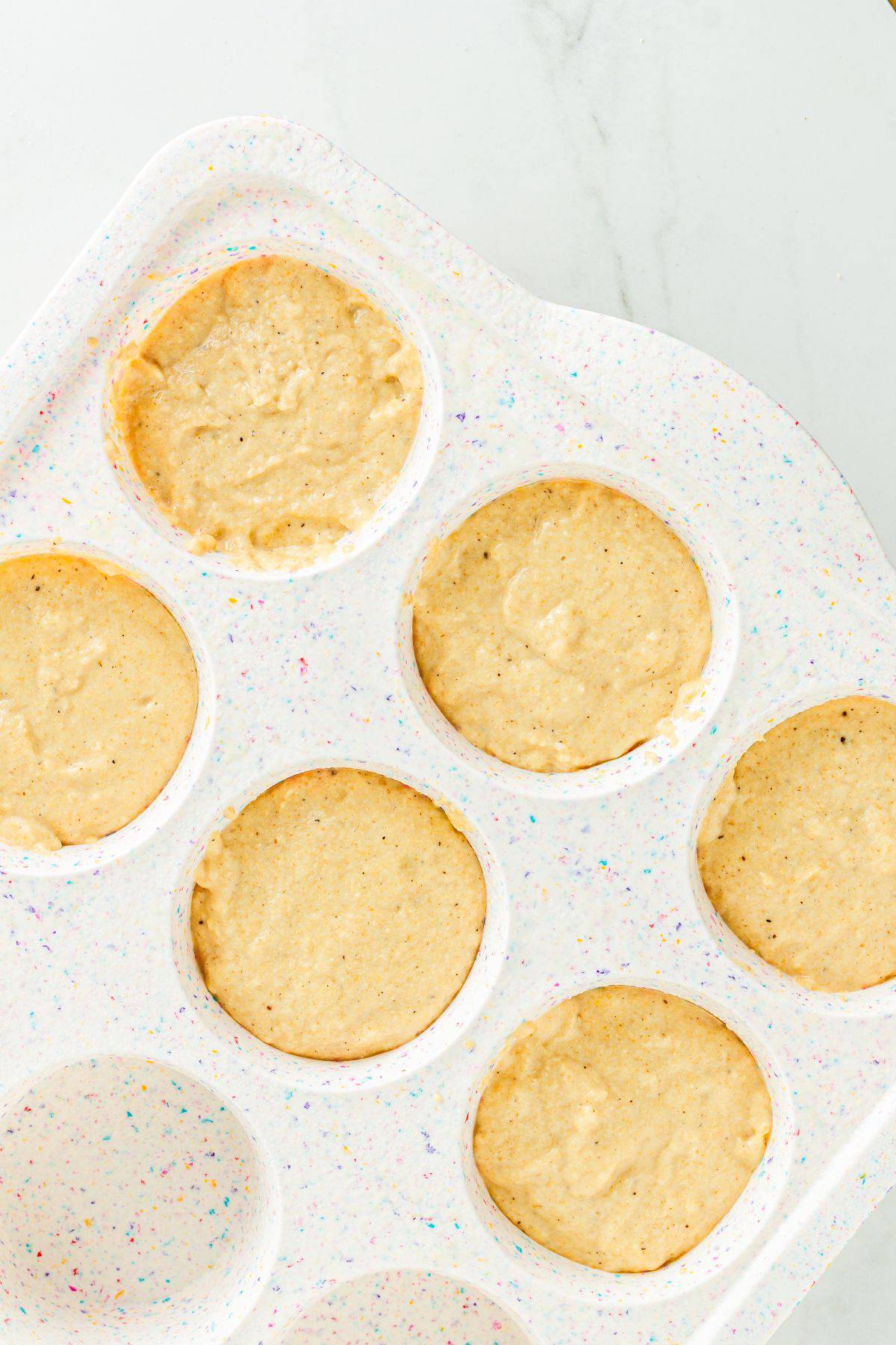 A muffin tin with pancake batter in it. 