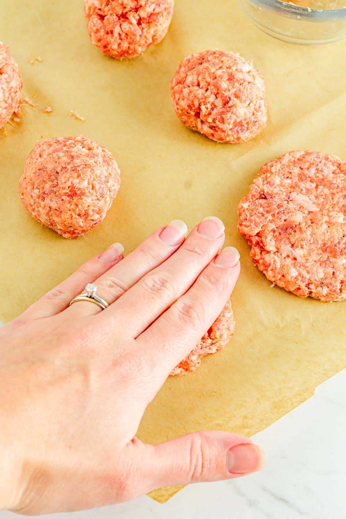 A person is making patties from ground sausage.