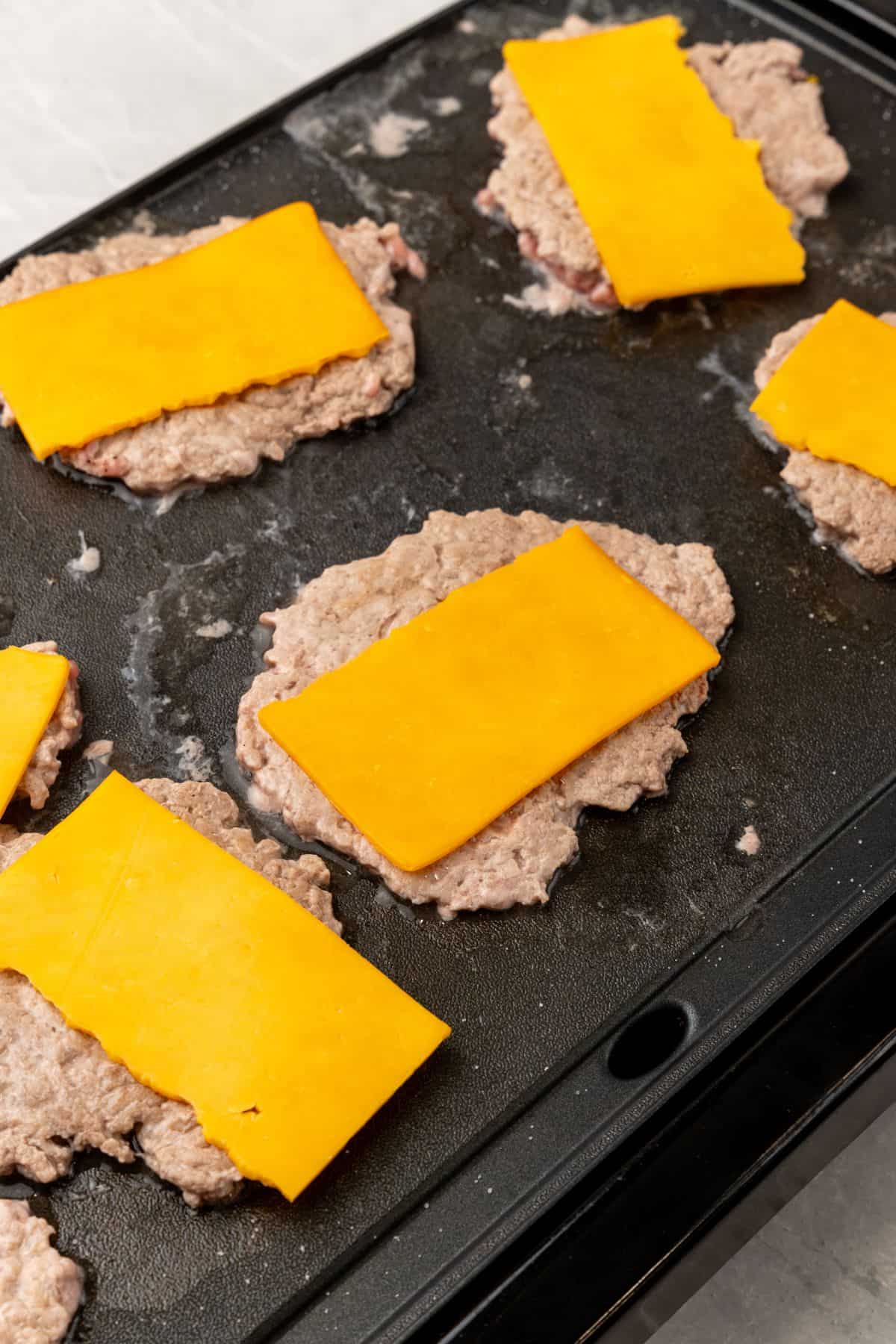 Smash burgers with cheese on a griddle.