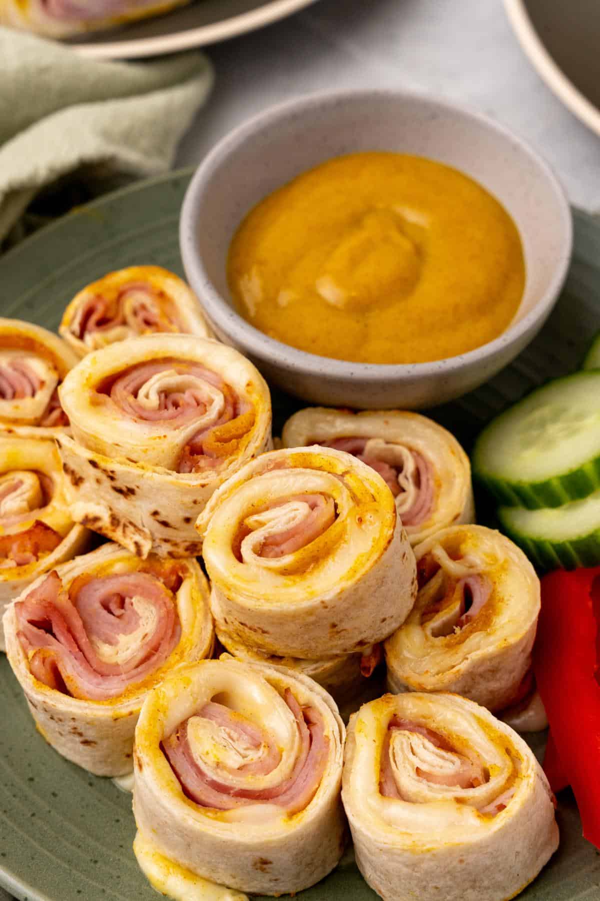 Cheesy ham roll ups on a plate.