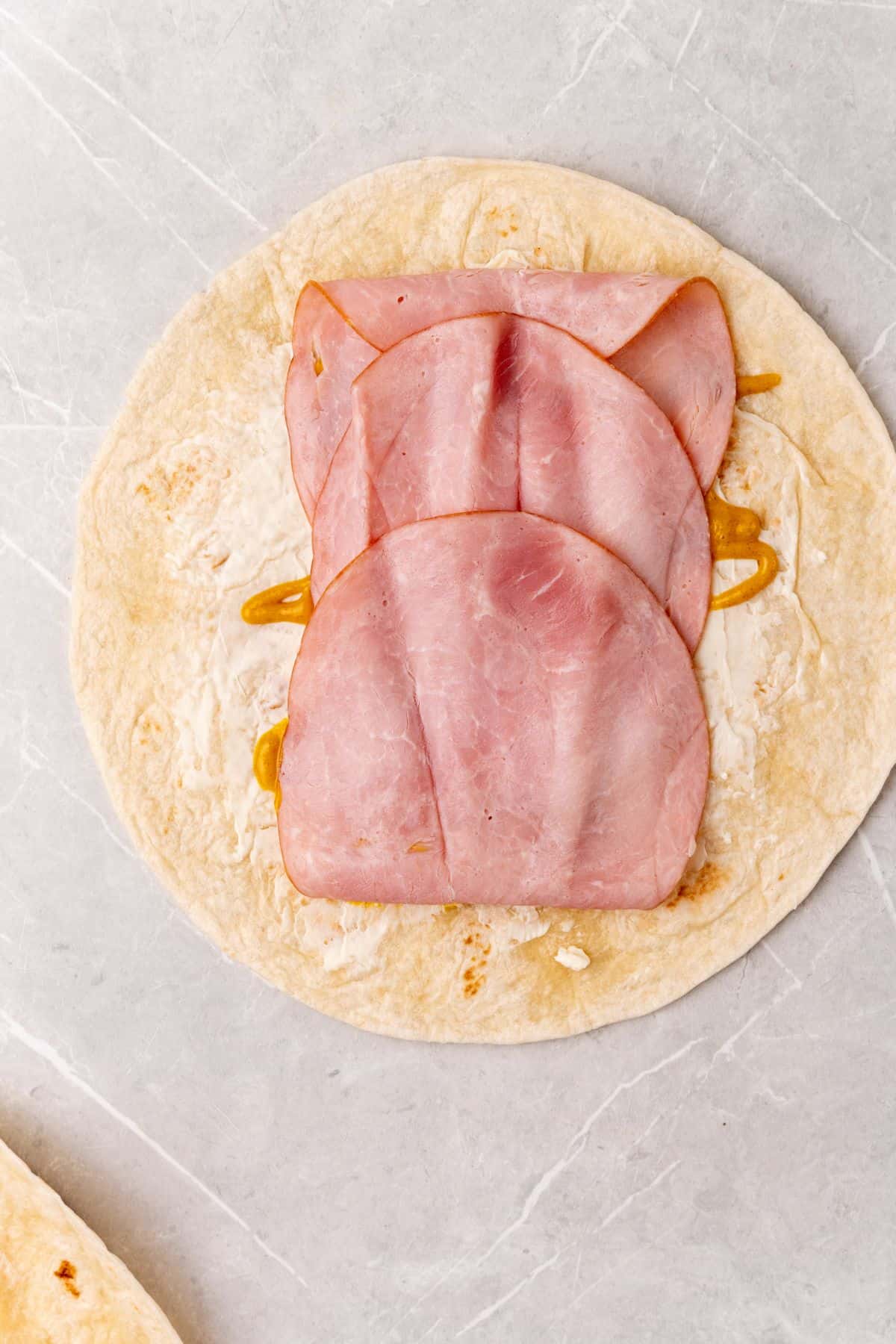 Ham and cheese wraps on a marble countertop.