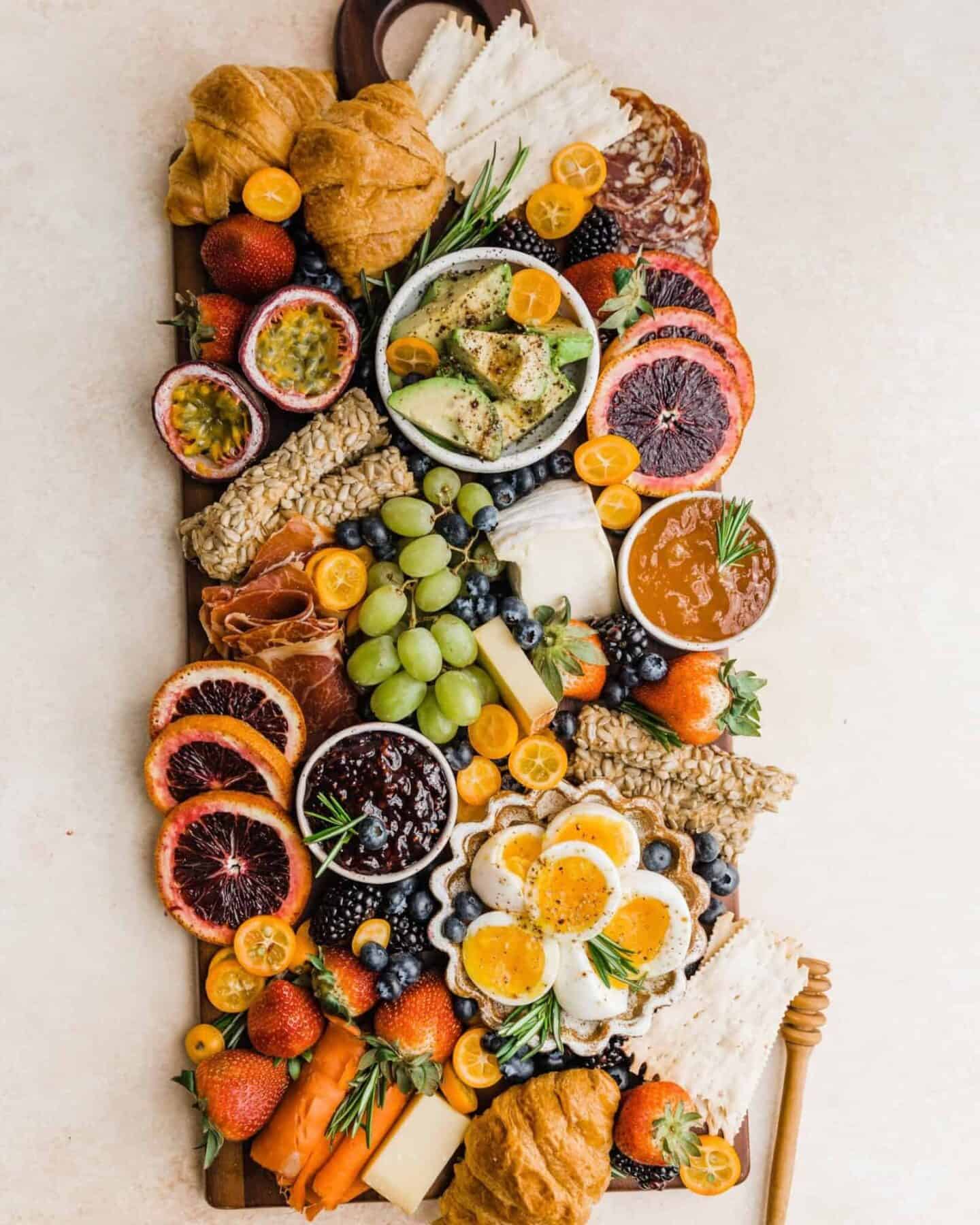 A colorful and diverse charcuterie board filled with an assortment of fruits, cheeses, meats, and pastries.