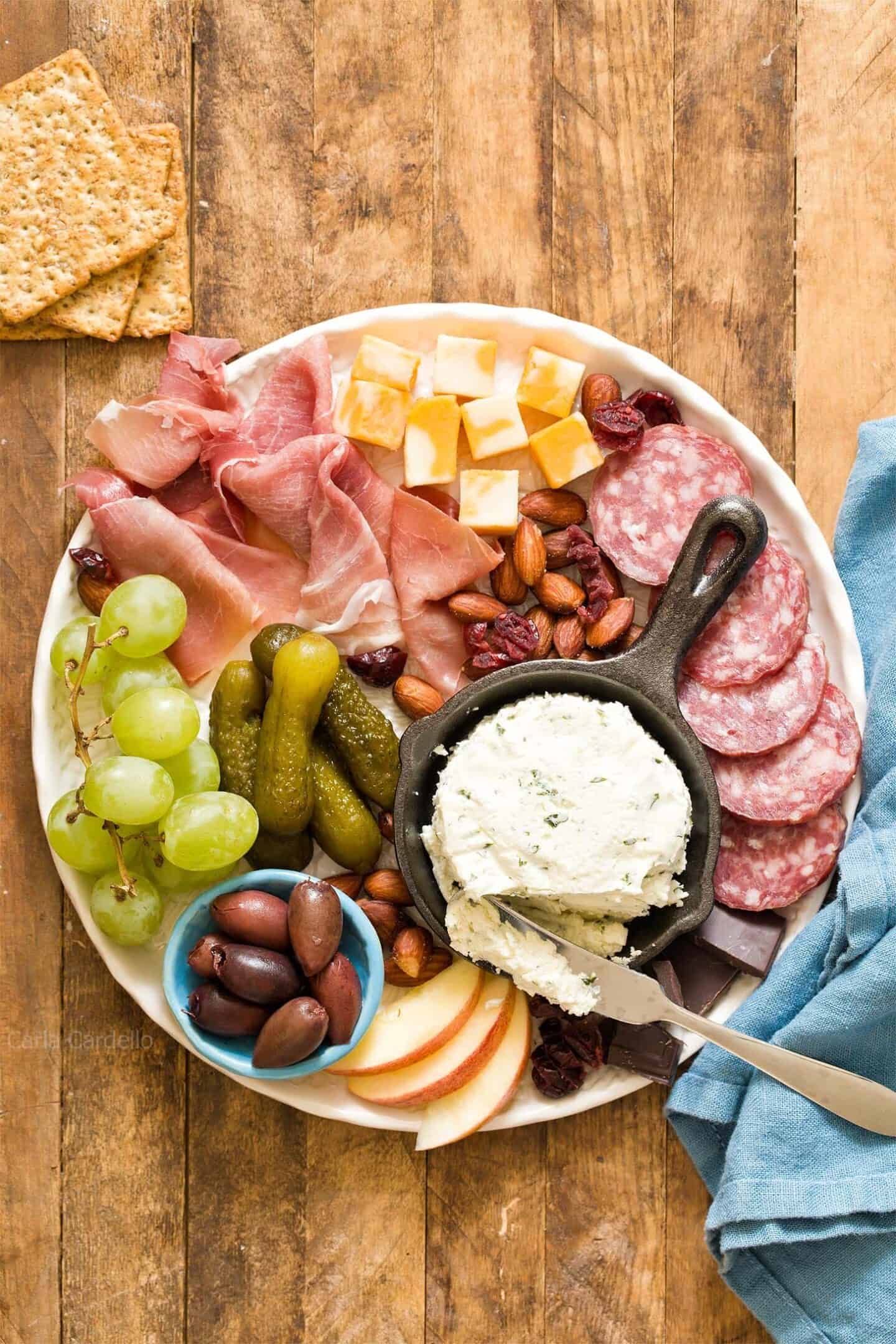 An assortment of cheeses, cured meats, nuts, and fruits neatly arranged on a serving platter.