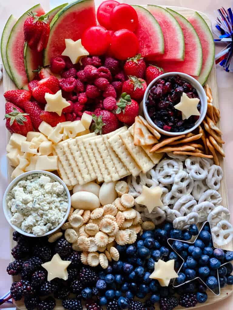 Assorted fruit and cheese platter with crackers and snacks, arranged in a colorful display.