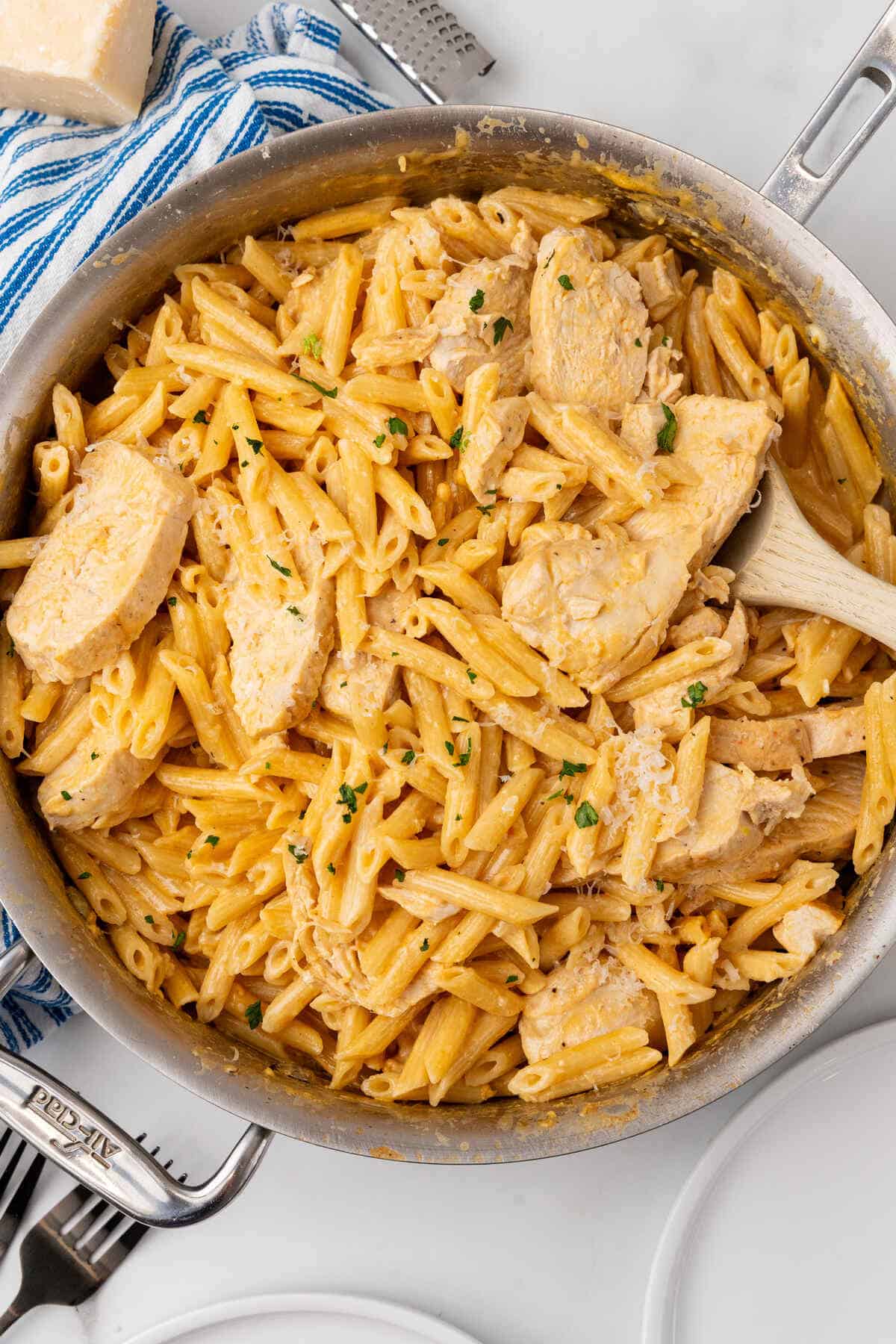 A skillet full of creamy buffalo chicken Alfredo pasta garnished with herbs.