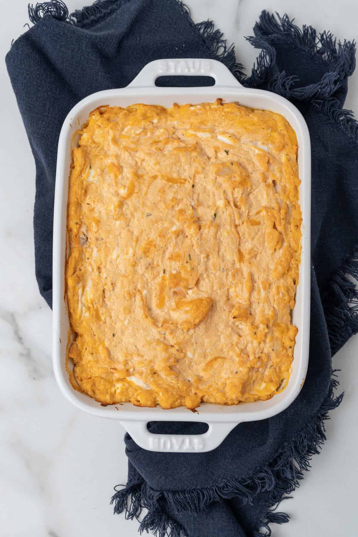 Cheesy buffalo chicken dip in a white dish with a blue napkin.