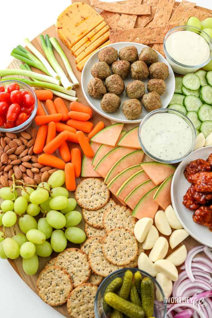 A colorful array of snacks featuring meats, cheeses, fruits, vegetables, nuts, and dips neatly arranged for a party platter.