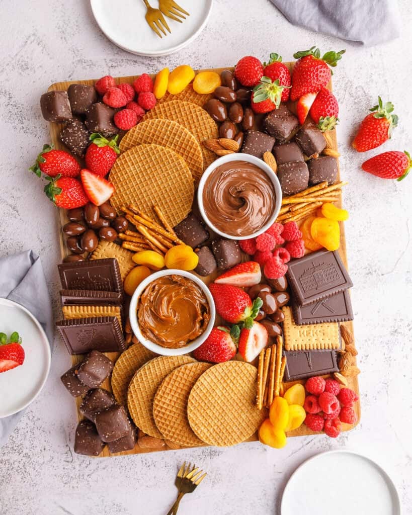 Assorted sweets and fruits platter featuring chocolate, cookies, strawberries, and dipping sauces.