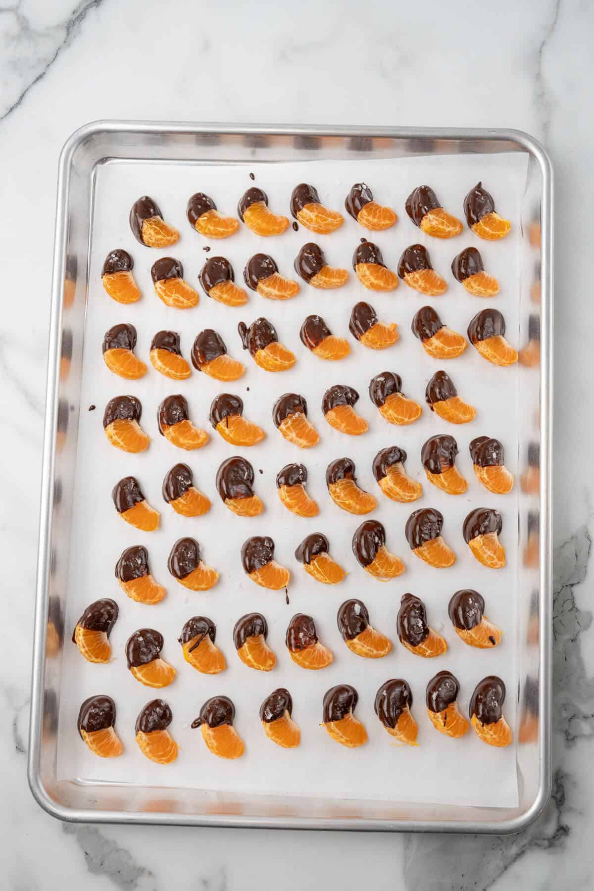 Chocolate covered oranges on a baking sheet. 