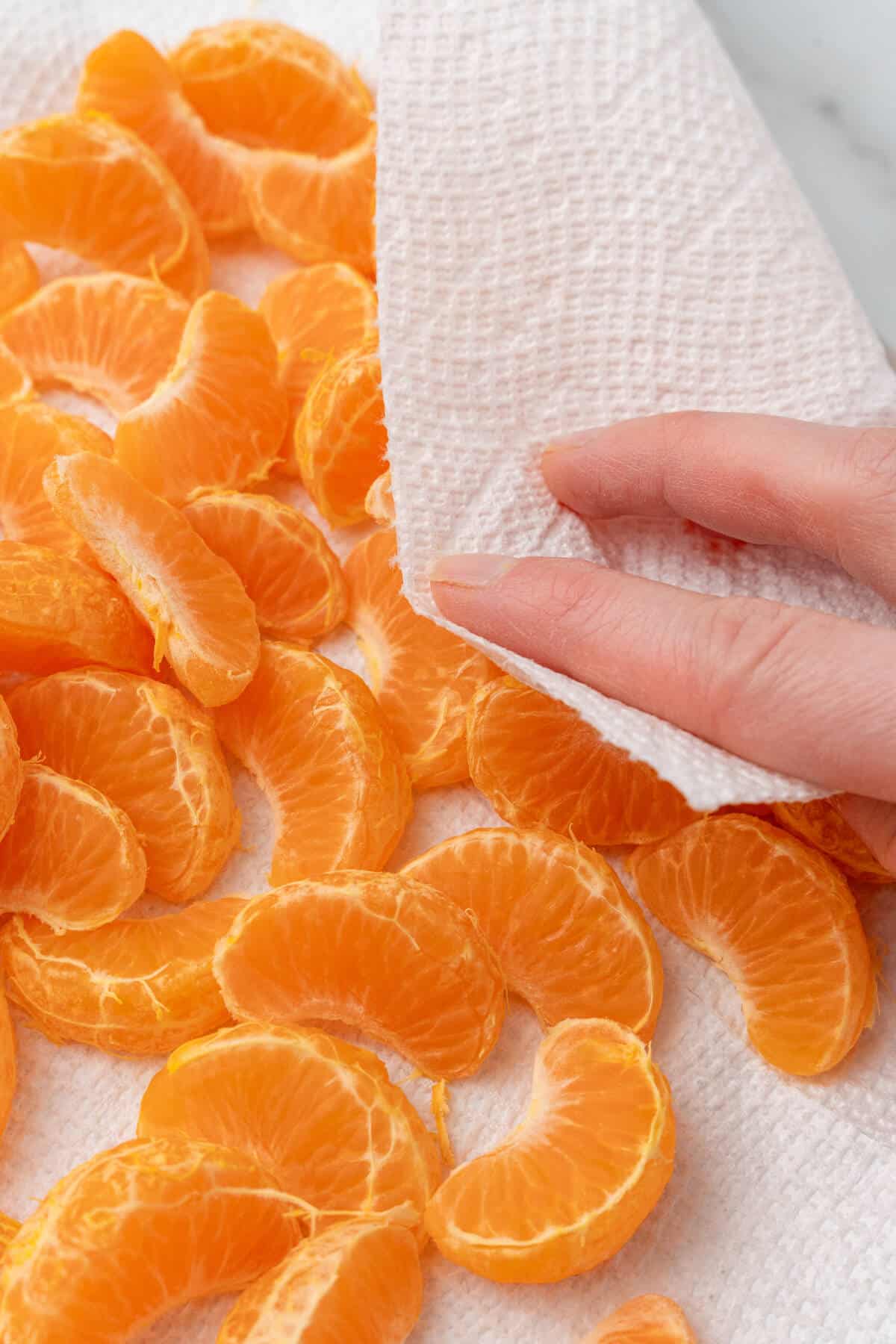 Orange segments being dried with a paper towel. 