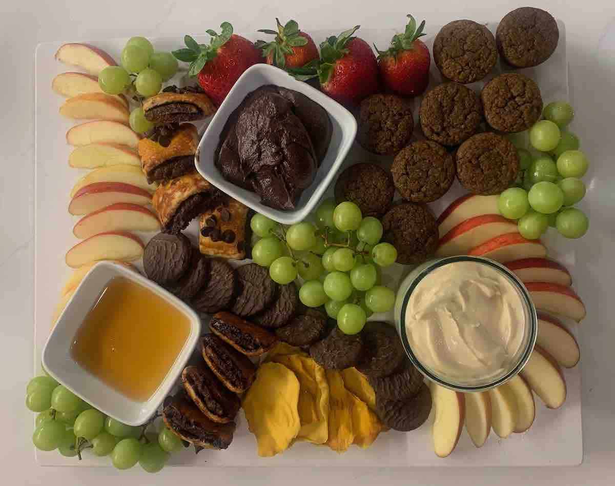 Assorted fruit and cookies platter with chocolate and cream dips.