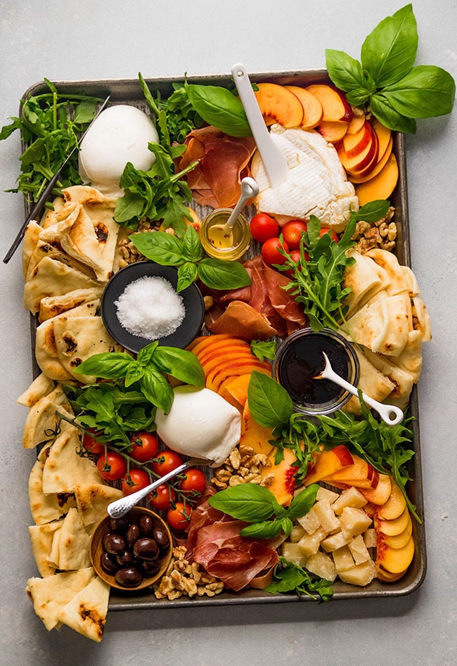 A colorful charcuterie board with an assortment of cheeses, cured meats, fruits, and nuts.