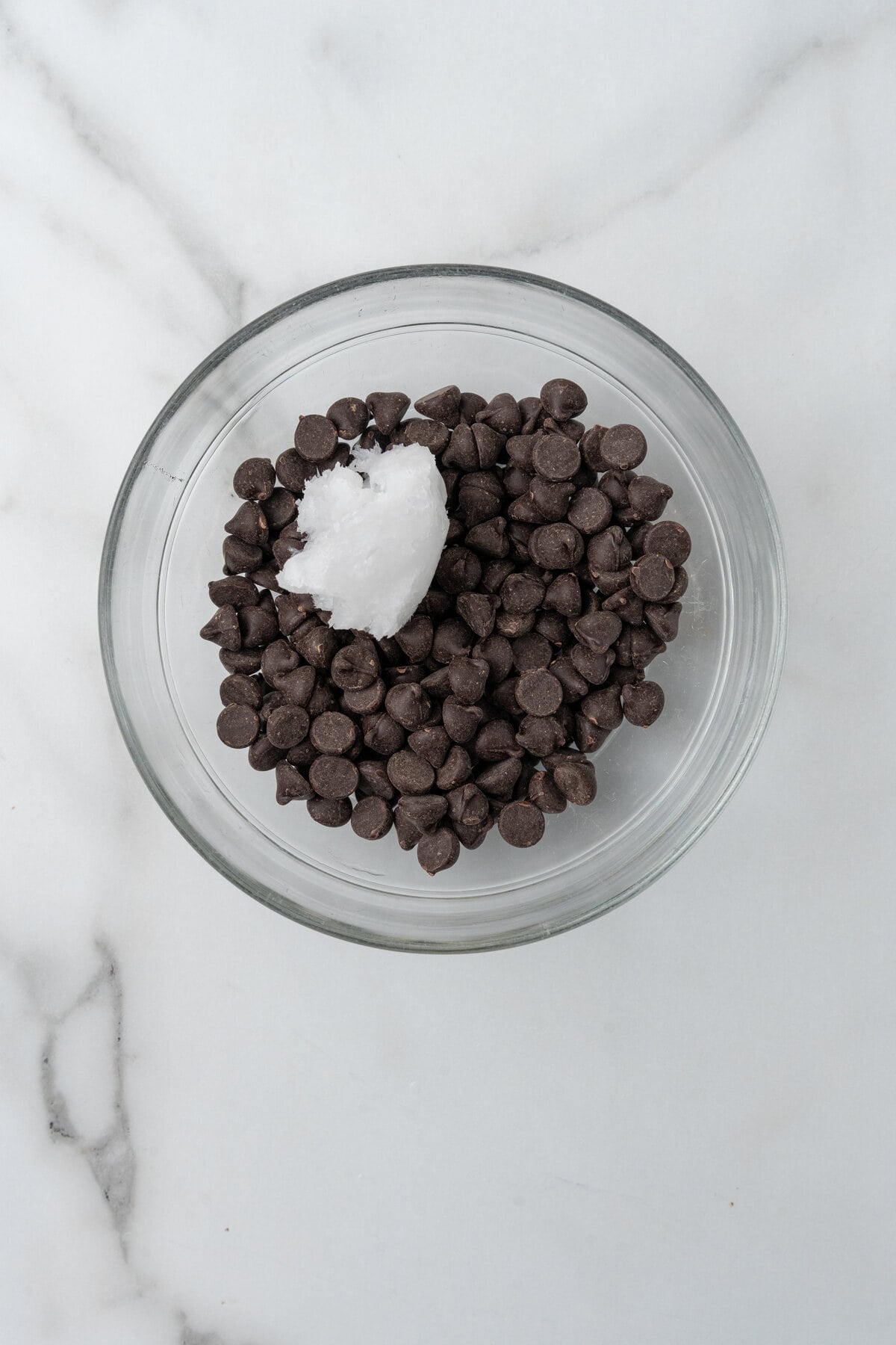 Dark chocolate chips and coconut oil, in a small glass bowl. 