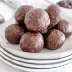 A stack of mint chocolate protein balls sits enticingly on a plate, with chocolate chips casually scattered nearby.