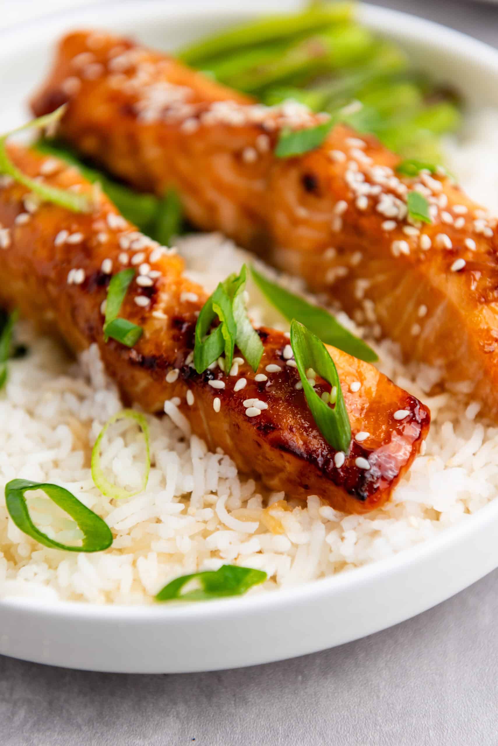 Savor the taste of teriyaki salmon fillets, perfectly grilled and topped with sesame seeds and green onions on a bed of white rice. Served alongside tender asparagus, this salmon recipe is easily adaptable for your air fryer.