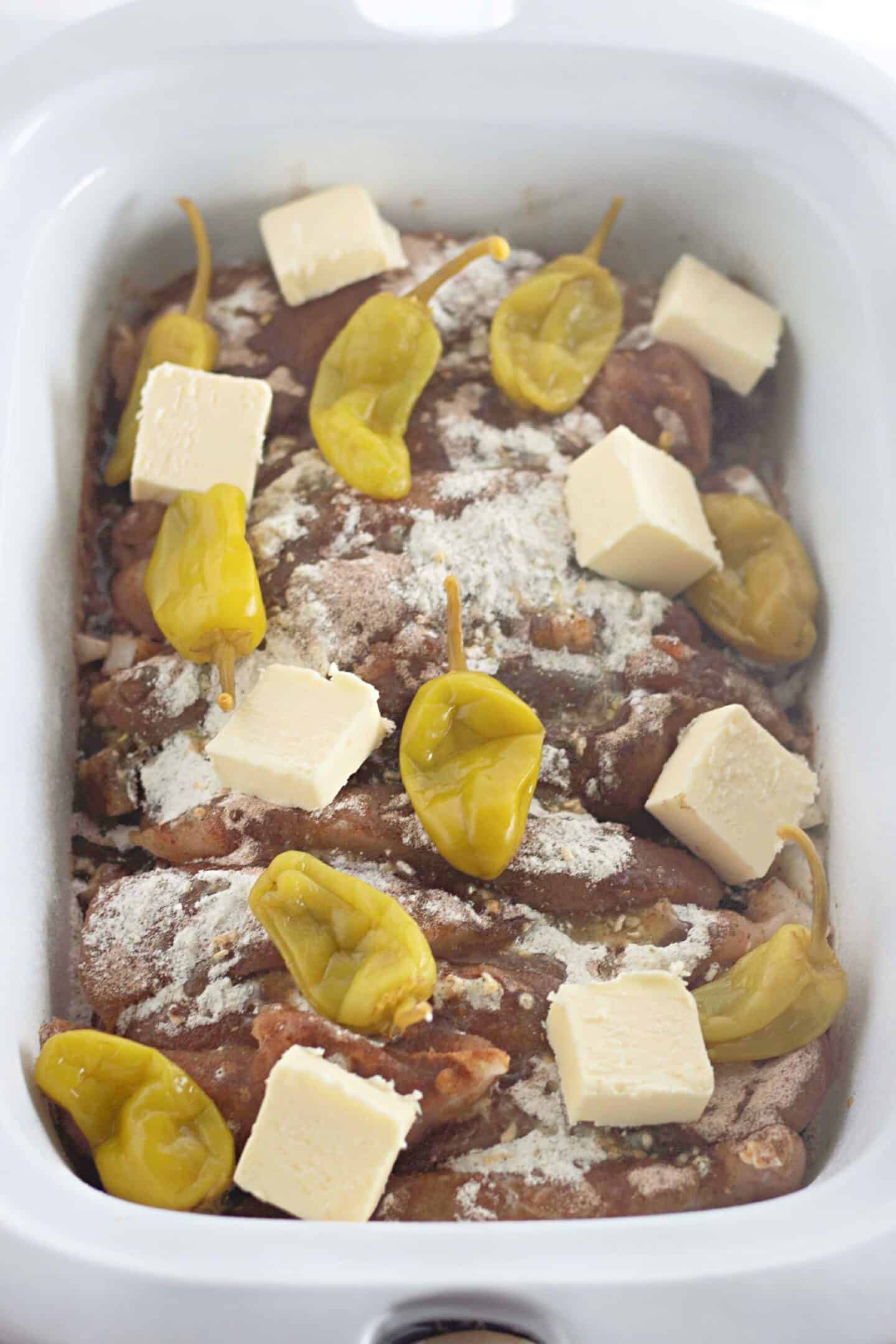 Mississippi Chicken with spices, butter cubes, and pepperoncini peppers in a slow cooker is a delightful southern cuisine staple.