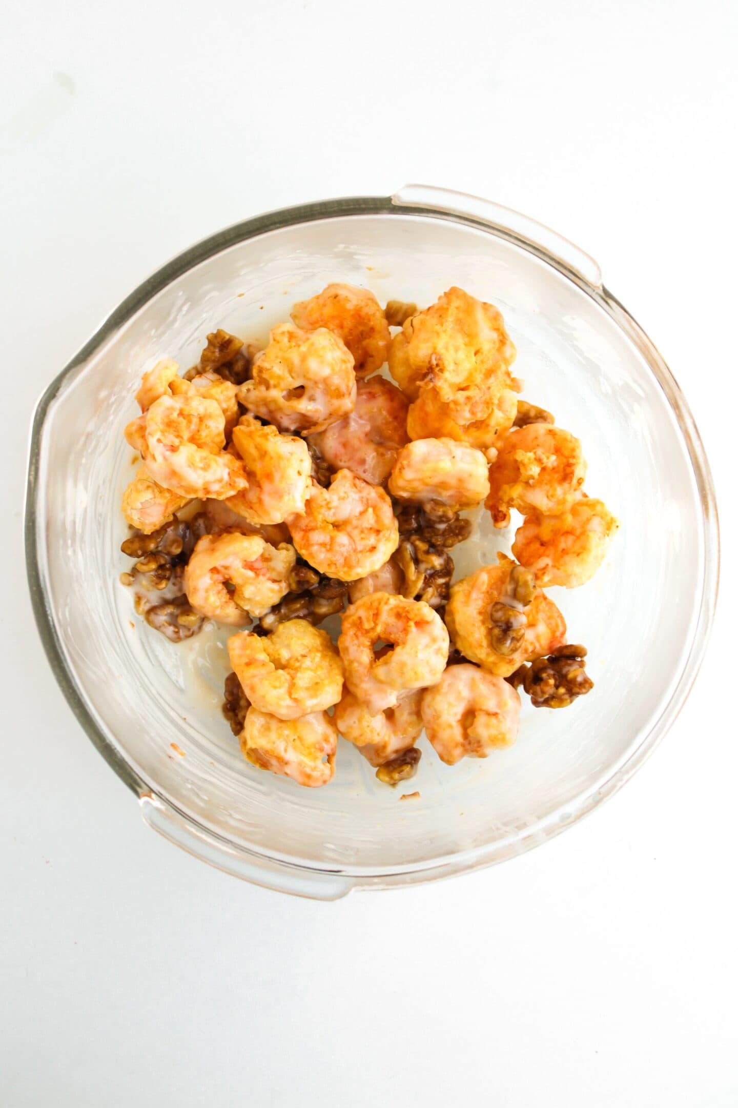 An air fryer masterpiece: a glass bowl showcasing honey walnut shrimp against a pristine white background.