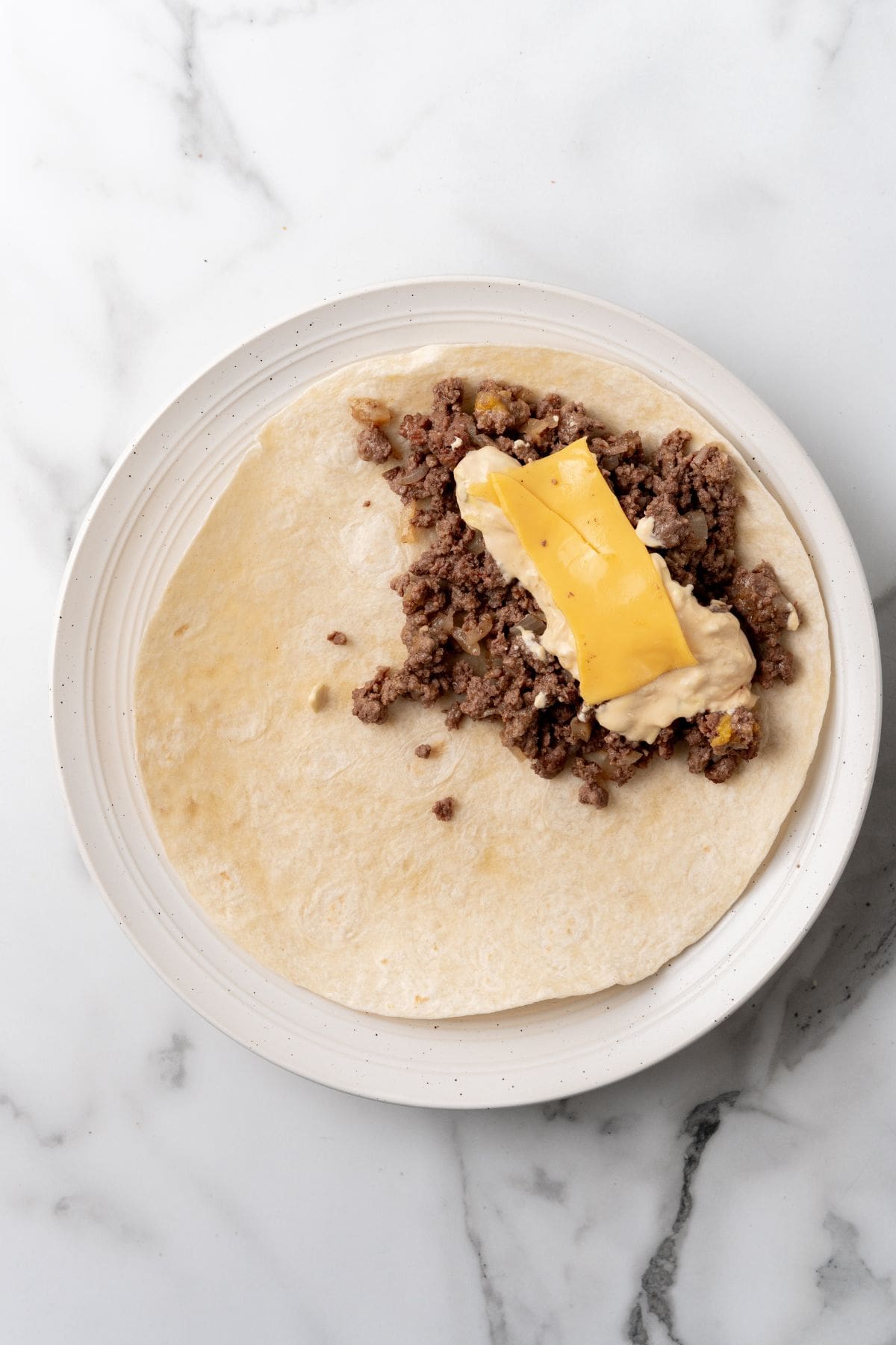 A tantalizing twist on a classic, this dish features a tortilla topped with savory ground beef and a slice of cheese, reminiscent of a Big Mac Quesadilla delight.