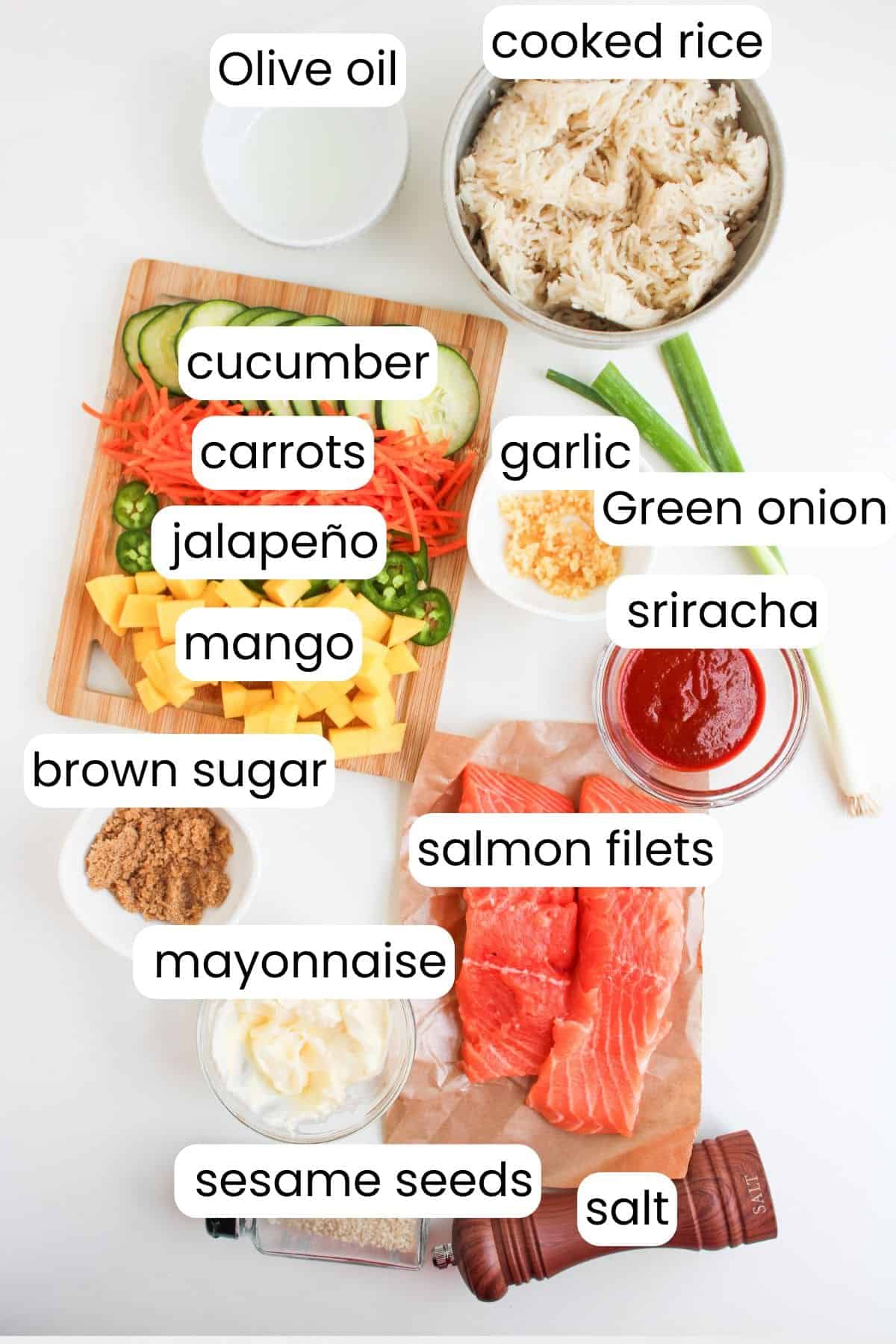 A top-down view of ingredients for Spicy Salmon Bowls, featuring cooked rice, salmon fillets, mayonnaise, sriracha, vegetables, mango, olive oil, brown sugar, garlic, sesame seeds, and salt.