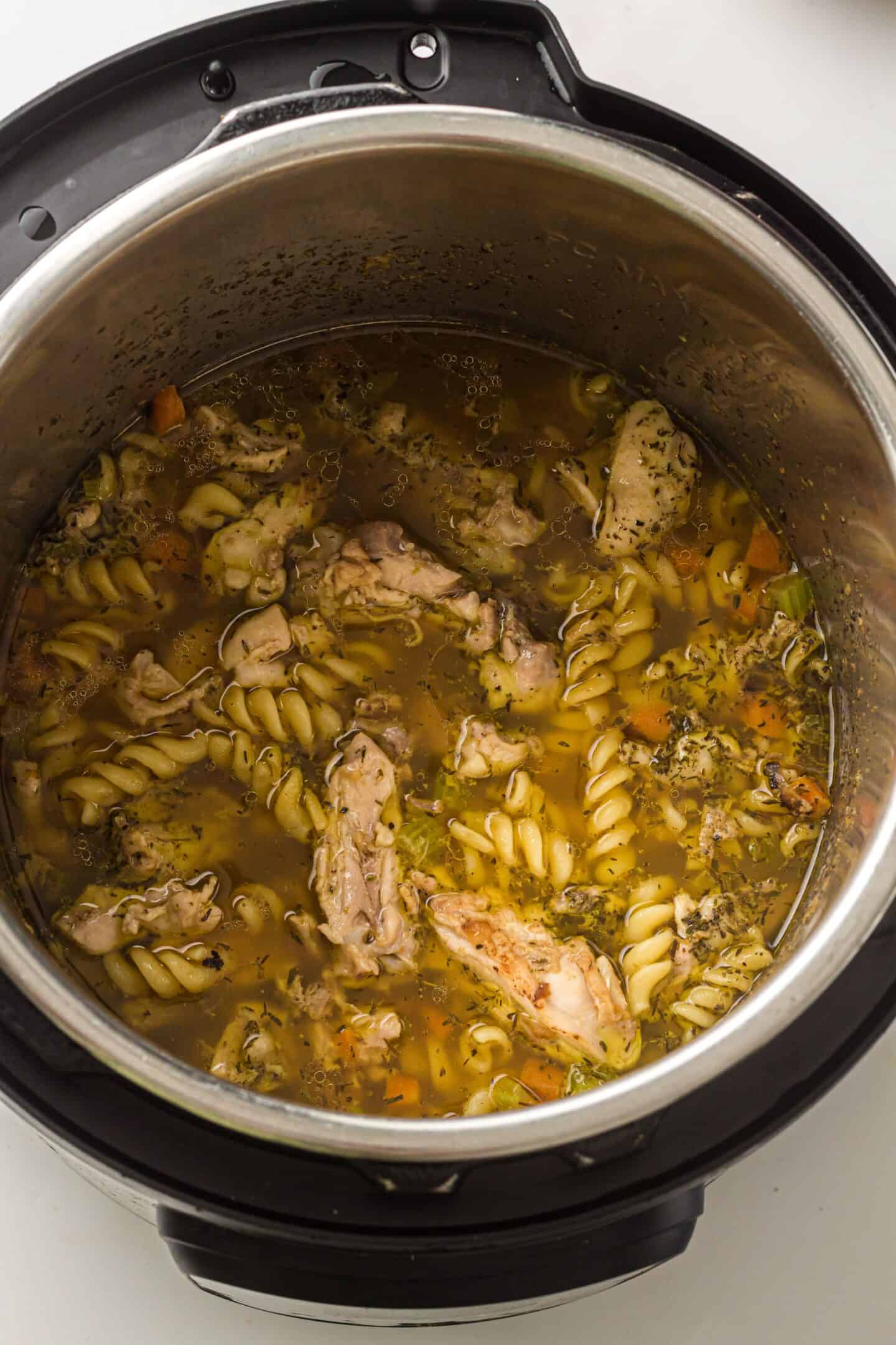 Chicken Noodle Soup with rotini pasta, vegetables, and herbs cooked in an Instant Pot, photographed from above.