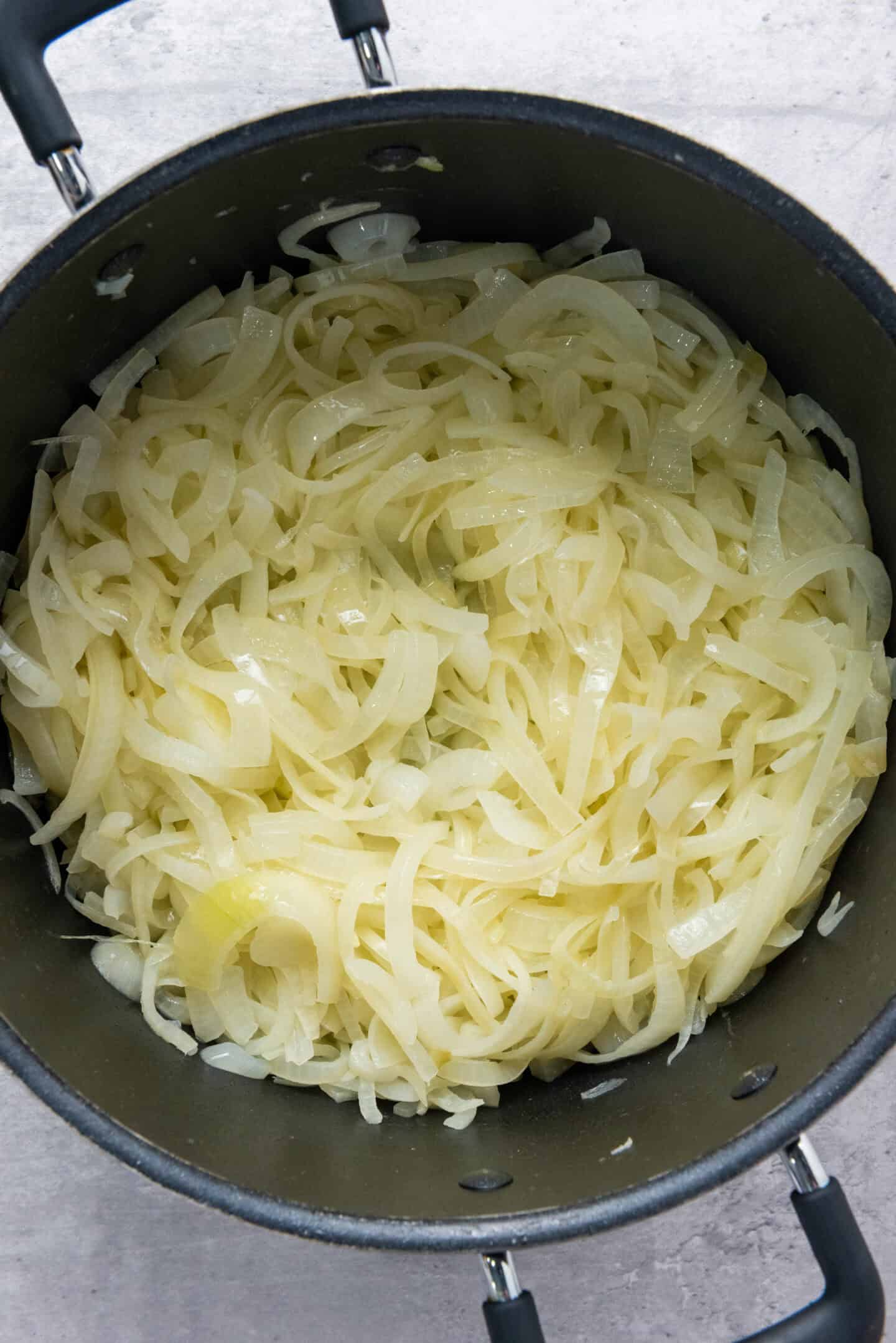 A pot filled with thinly sliced onions being cooked, viewed from above—perfect as the first step in making classic French Onion Soup.