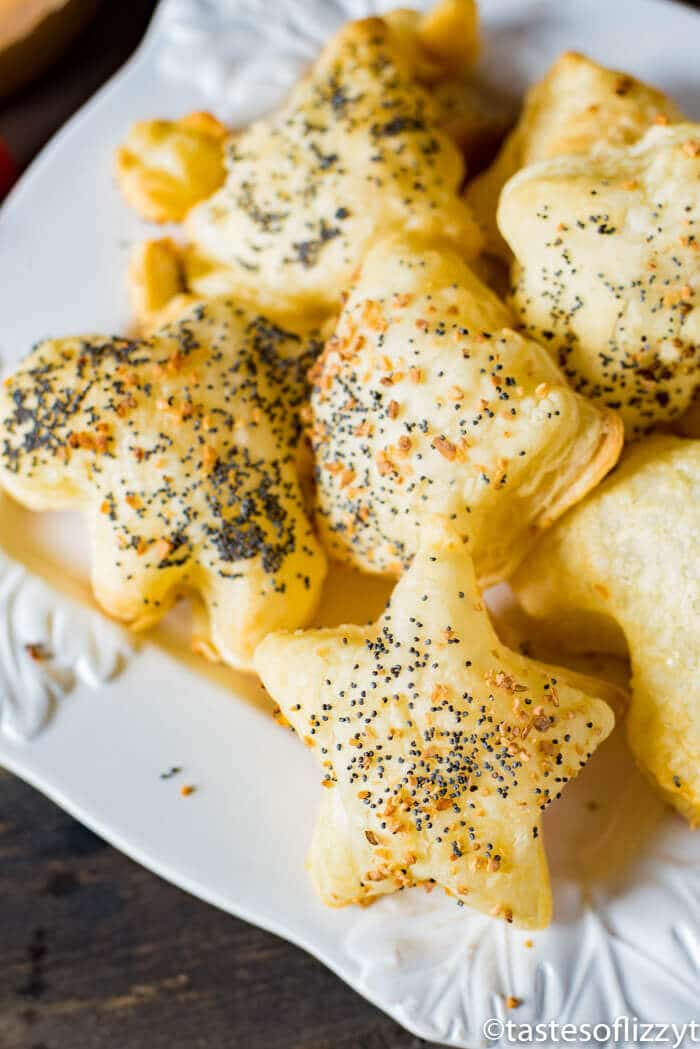 Star-shaped puff pastries topped with poppy seeds and seasoning are arranged on a white plate, making them a festive addition to any Christmas Dinner Menu.