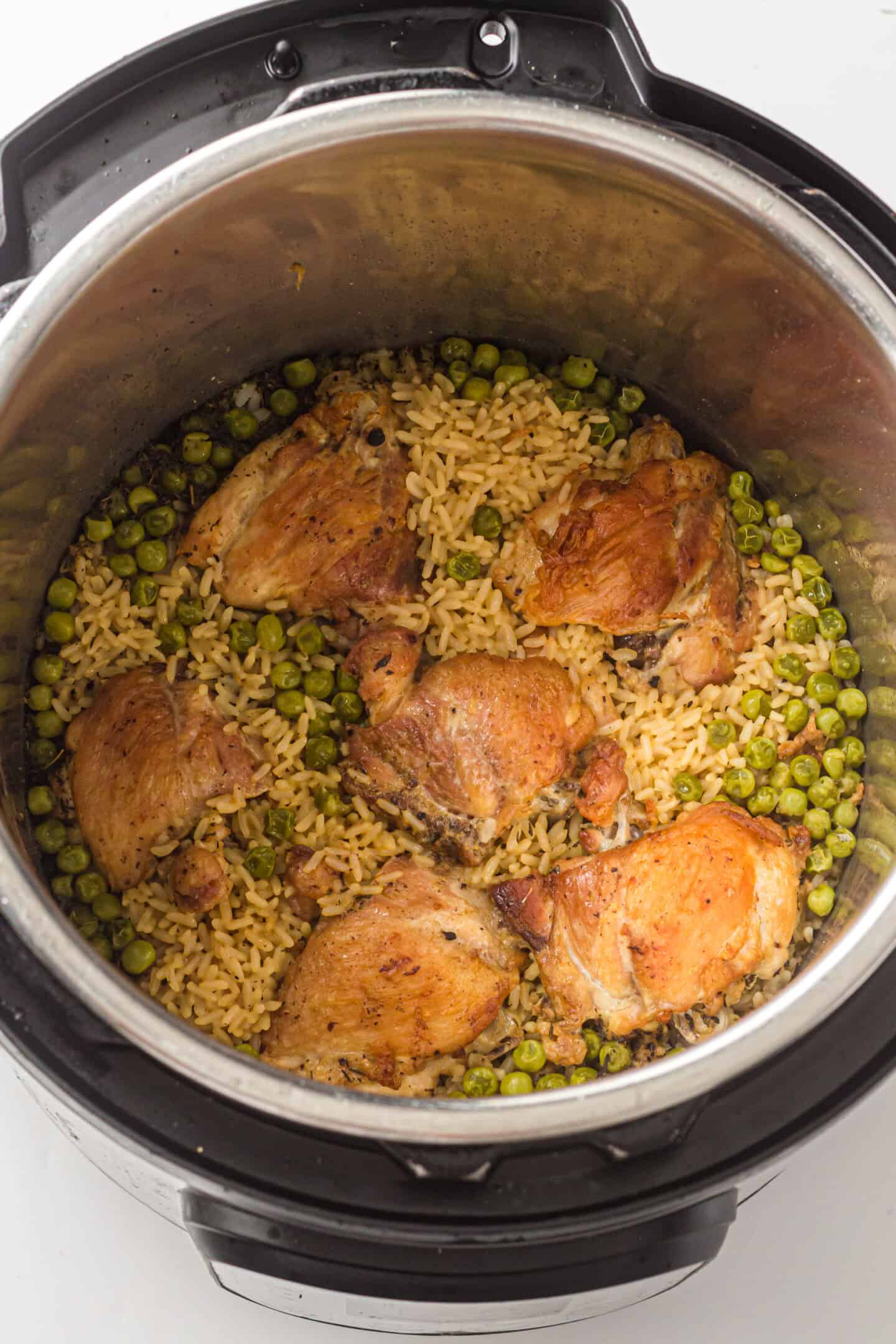 Chicken thighs, rice, and peas are perfectly cooked together in the Instant Pot, viewed from above.