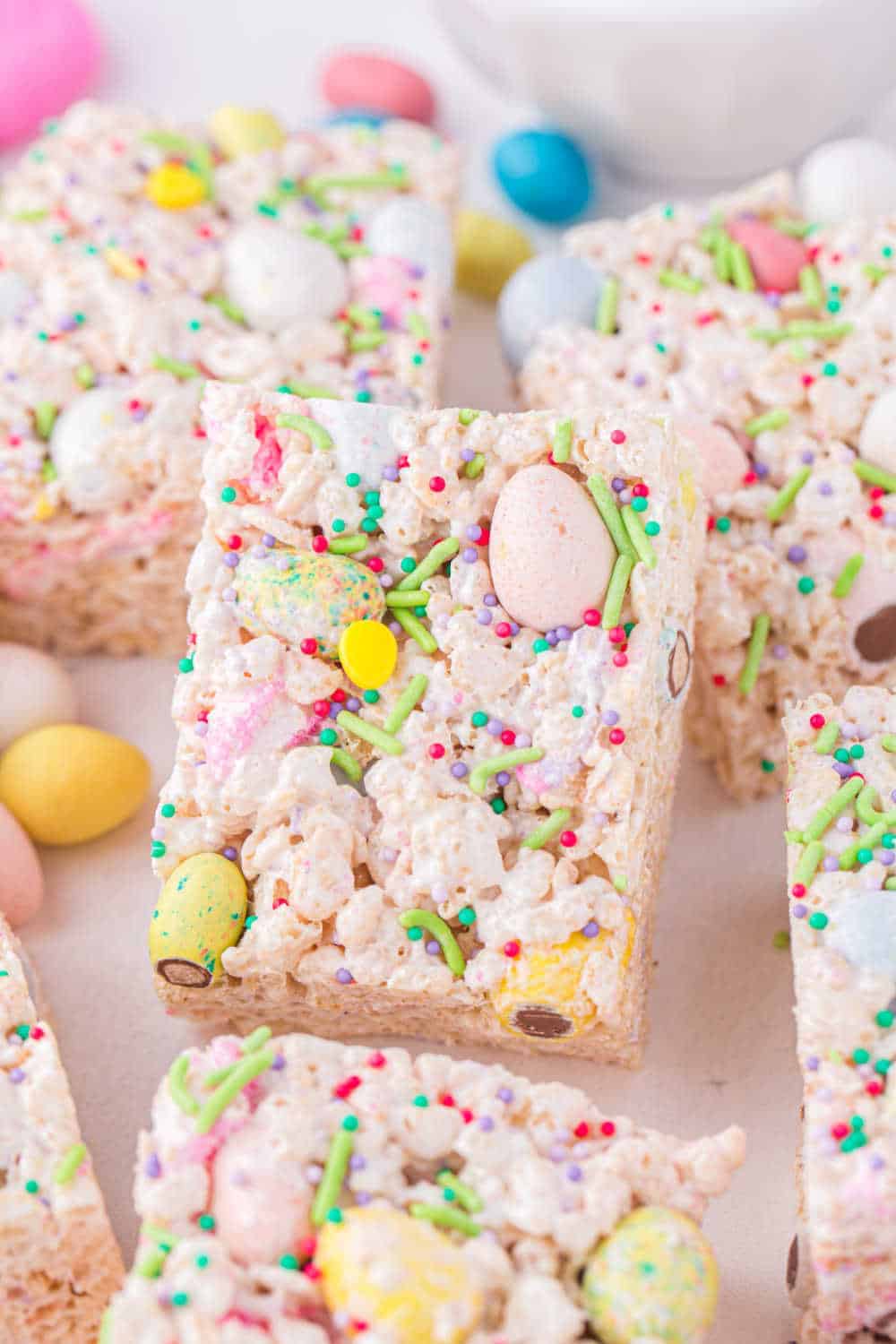 A close-up of rice crispy treats topped with colorful sprinkles and candy-coated chocolate eggs—perfect Easter party food.