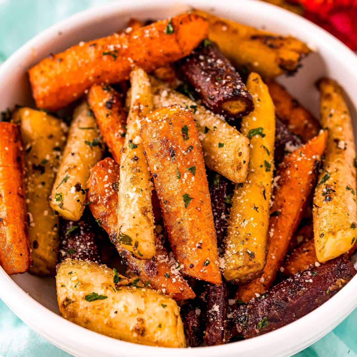 A bowl of roasted multicolored carrots, seasoned with herbs and grated cheese—a vibrant choice for Easter side dishes.