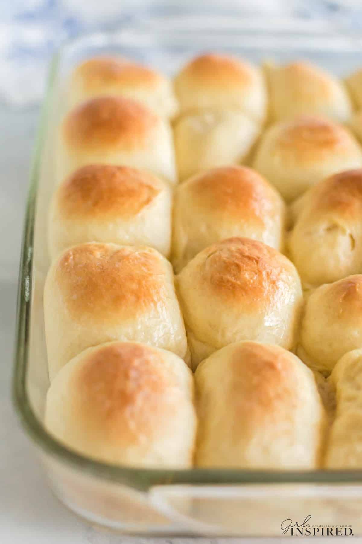 A glass baking dish filled with golden brown, freshly baked dinner rolls—perfect as Easter side dishes for your holiday table.
