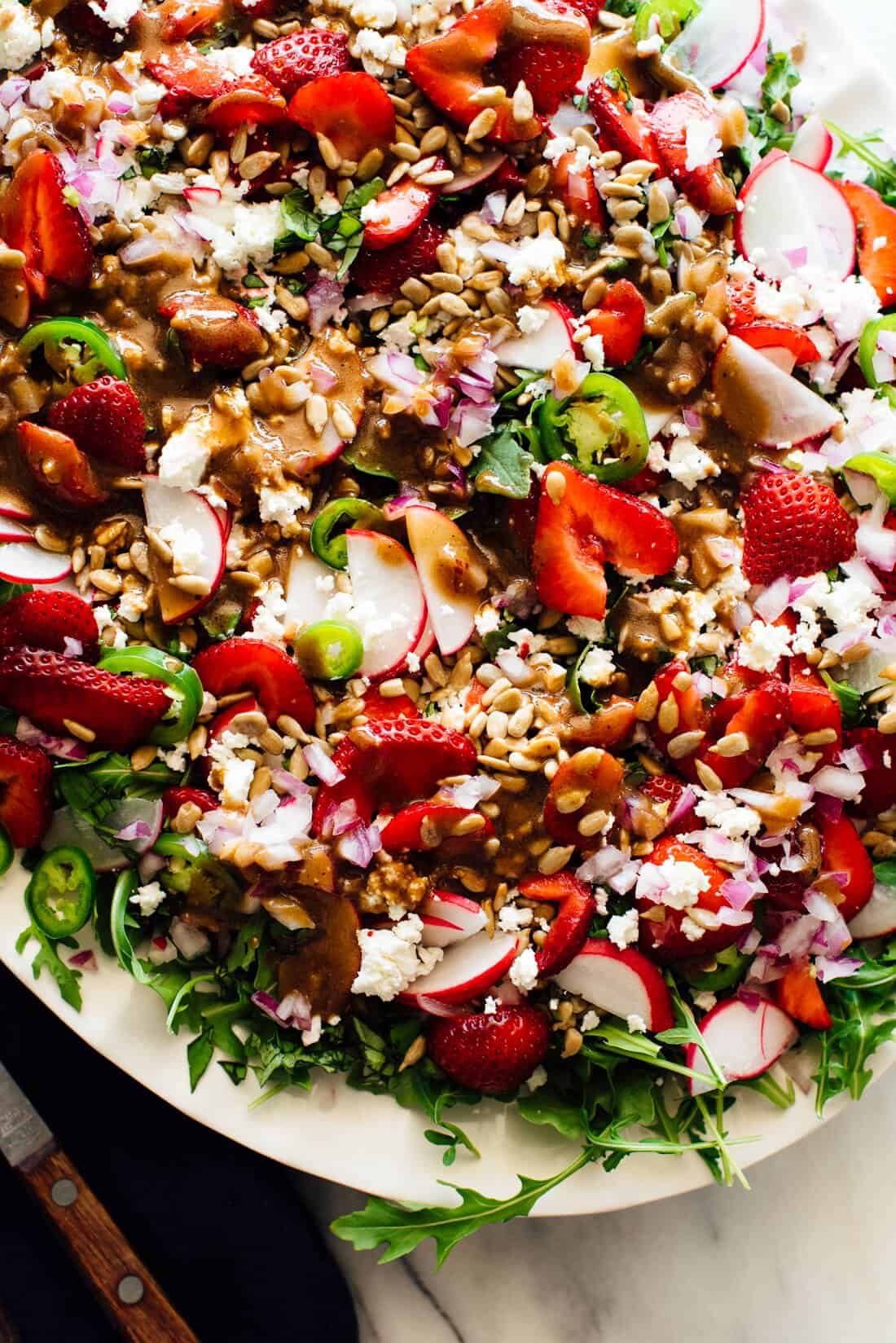 A vibrant salad with arugula, strawberries, radishes, jalapeños, feta, sunflower seeds, and red onion—perfect for your Spring Dinner Party menu.