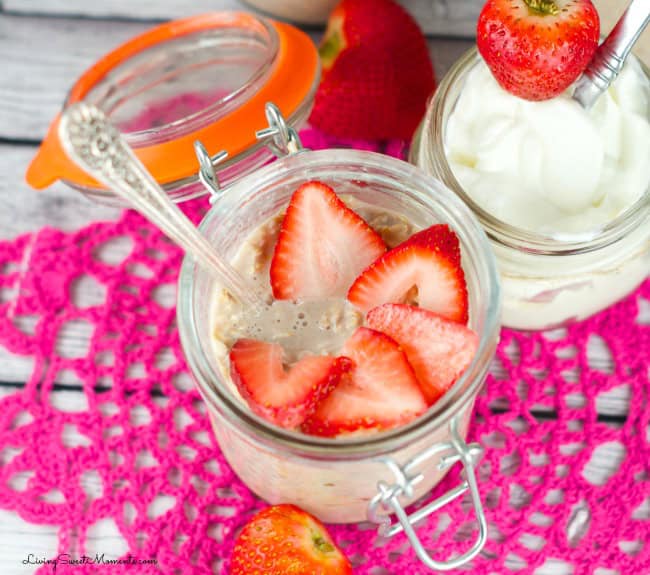 A glass jar of Overnight Oats without chia seeds, topped with sliced strawberries, sits on a pink crochet mat next to a jar of yogurt and whole strawberries. Perfect for those seeking delicious overnight oats recipes.