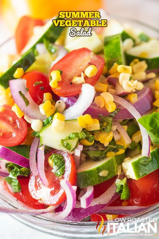 A bowl of summer vegetable salad with sliced cucumbers, cherry tomatoes, red onions, corn, and herbs—perfect for those who love summer vegetable side dishes. Text overlays read "Summer Vegetable Salad" and "The Slow Roasted Italian.