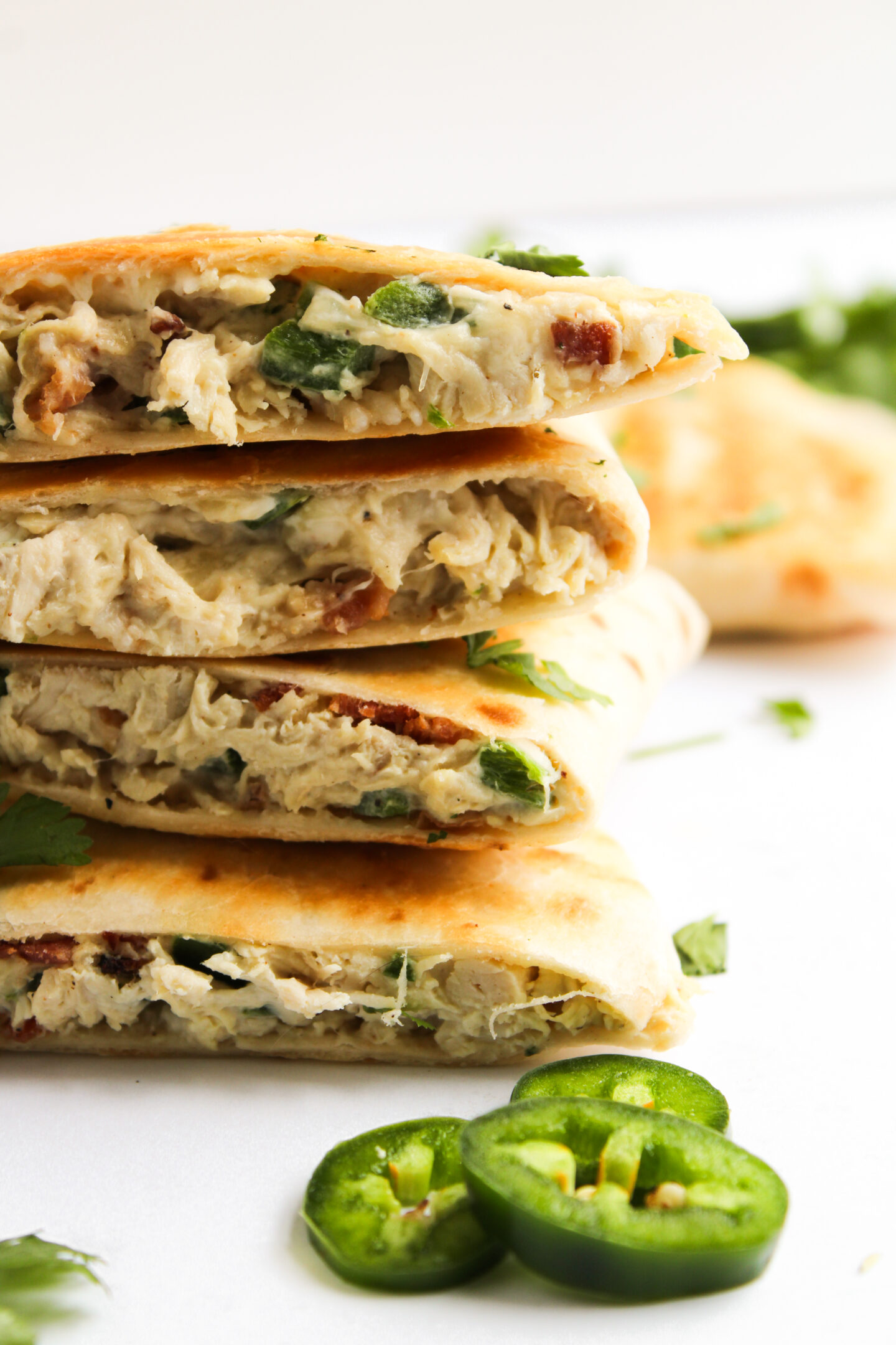 Stack of stuffed flatbreads filled with shredded chicken and green peppers, garnished with chopped herbs—perfect for summer Dinner Ideas. Sliced jalapeños add a spicy kick, making this one of the must-try June Recipes.