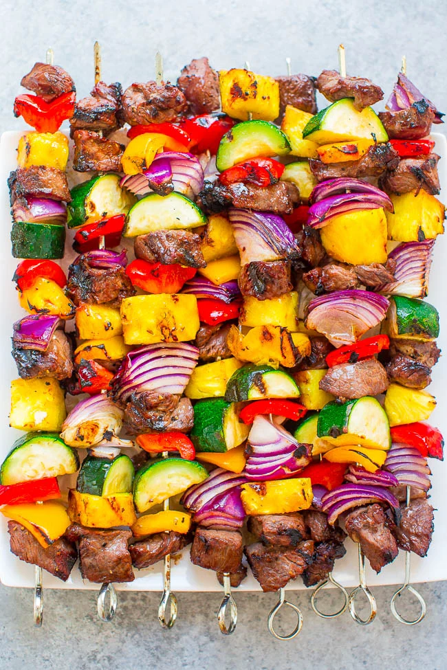 A tray of grilled skewers with beef, red onion, bell peppers, zucchini, and pineapple arranged in rows—perfect for a delicious Father's Day dinner or fresh summer dinner ideas.