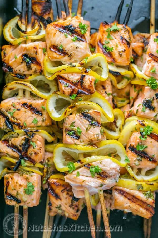 Grilled salmon and lemon slices threaded on skewers, garnished with chopped parsley—a perfect choice for healthy grilled dinners.
