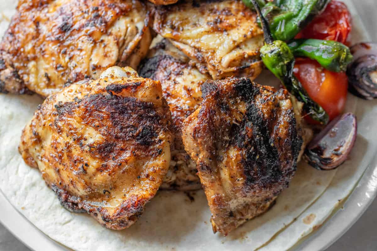 Enjoy a taste of summer with grilled chicken thighs served on a tortilla, topped with roasted green peppers, tomatoes, and red onion.