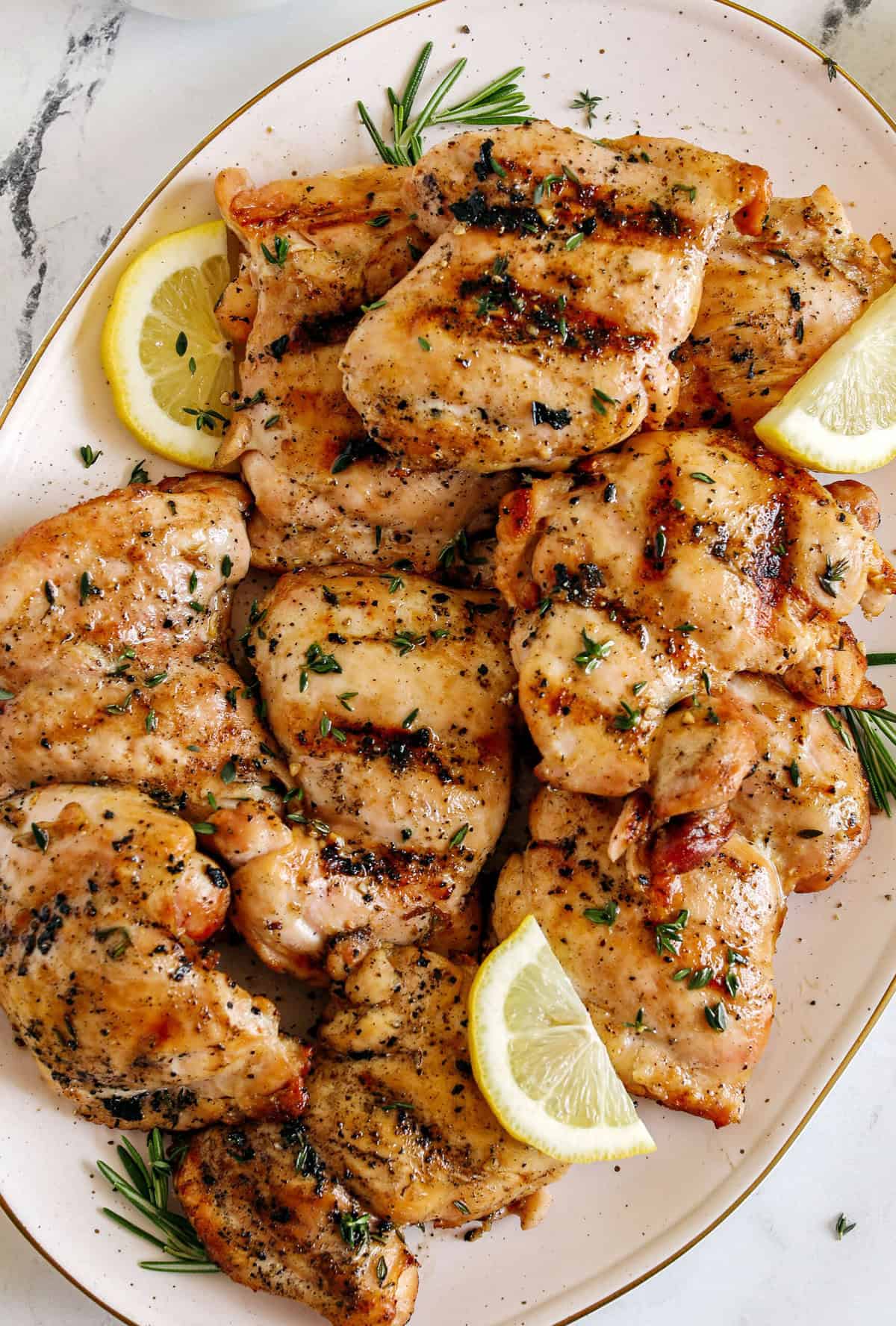 A plate of grilled, seasoned chicken thighs garnished with fresh herbs and lemon wedges—perfect for those seeking Healthy Grilled Dinners or inspired by flavorful Grilled Dinner Recipes.