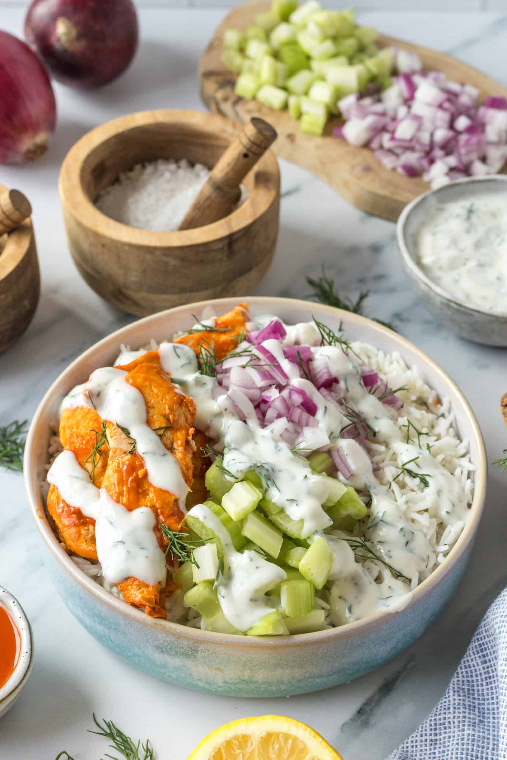 Finished buffalo chicken bowl with rice, celery, red onion, ranch, and dill.