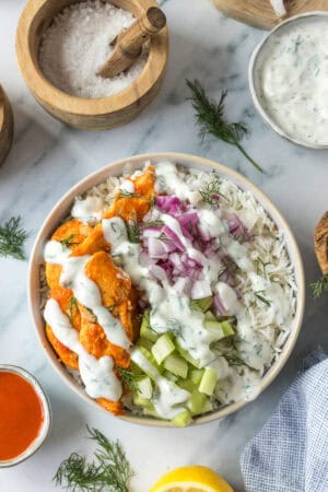 Buffalo chicken bowl with rice, celery, red onion, ranch dressing, and fresh dill.