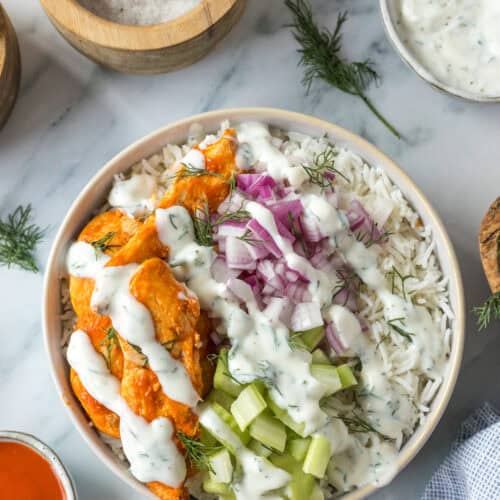 Buffalo chicken bowl with rice, celery, red onion, ranch dressing, and fresh dill.