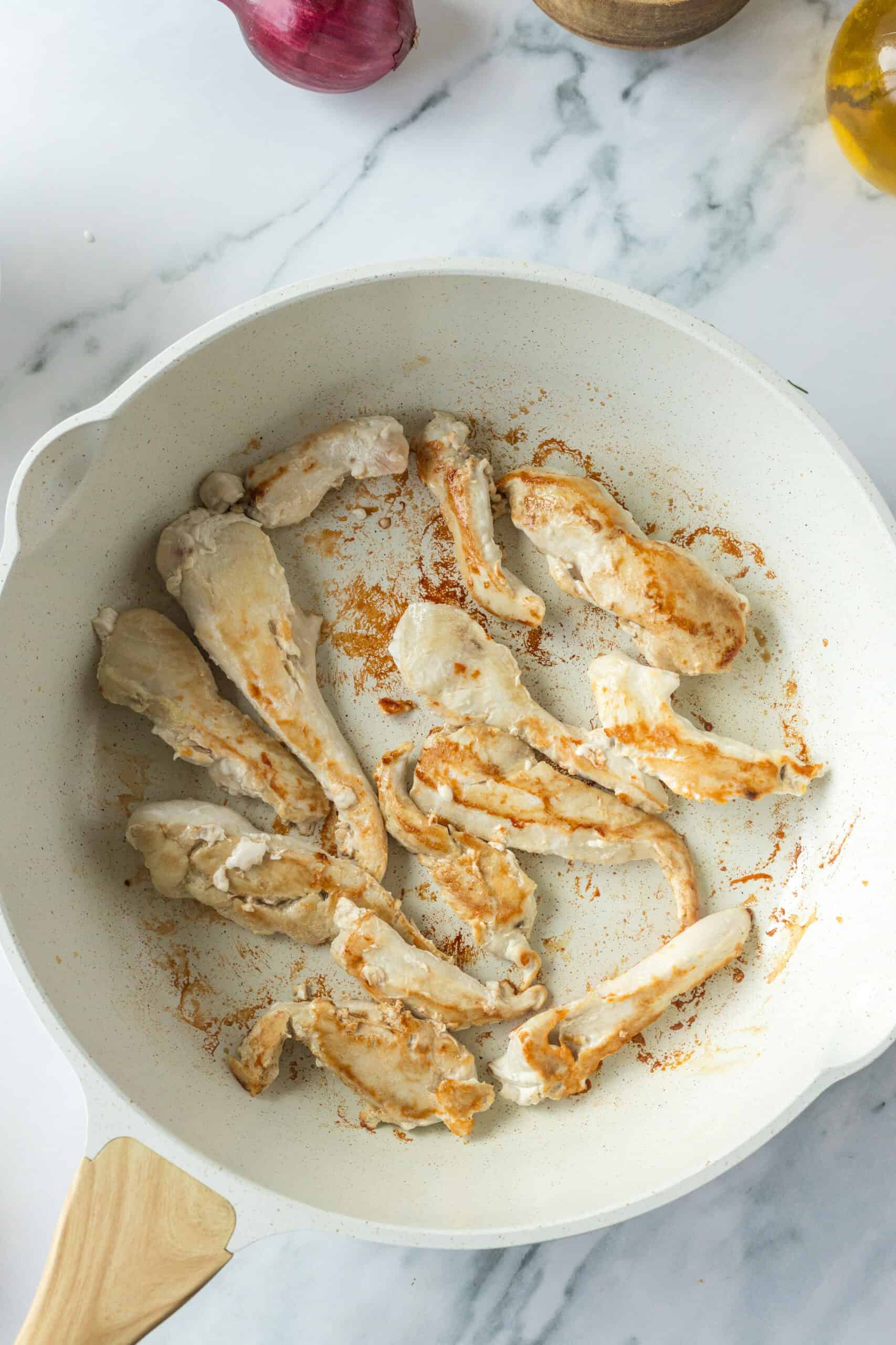 Chicken cooking in a skillet until golden brown.