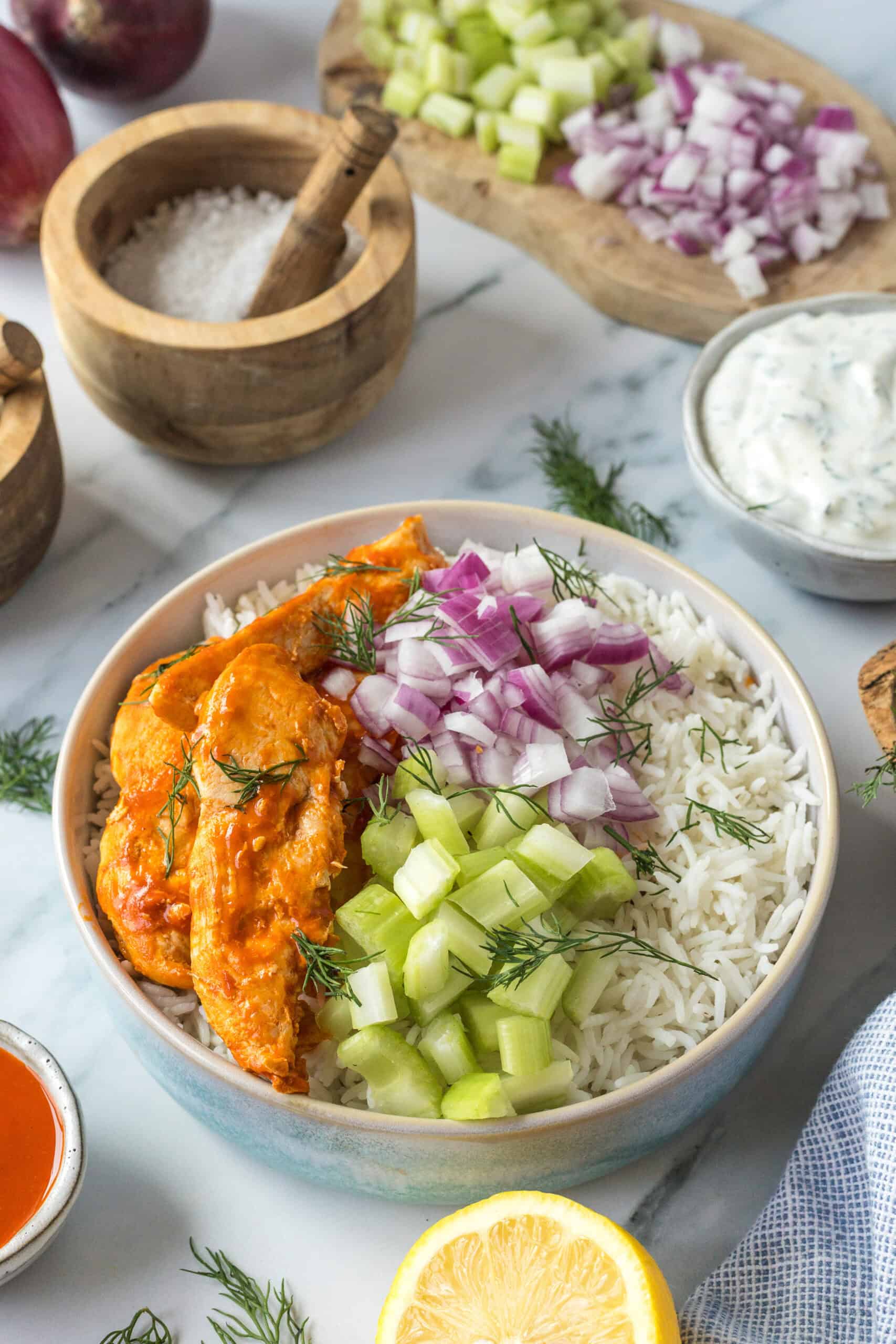 Buffalo chicken, rice, celery, and red onion arranged in a bowl.