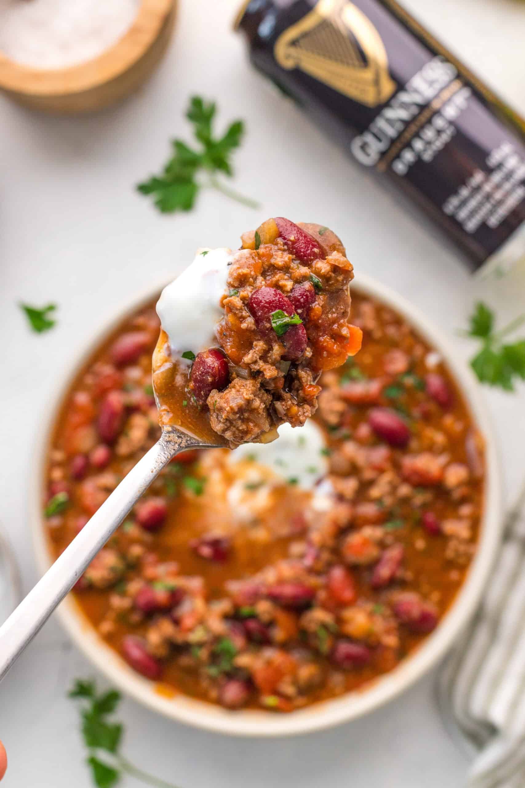 Spoonful of Guinness chili with beef, kidney beans, tomatoes, and sour cream.