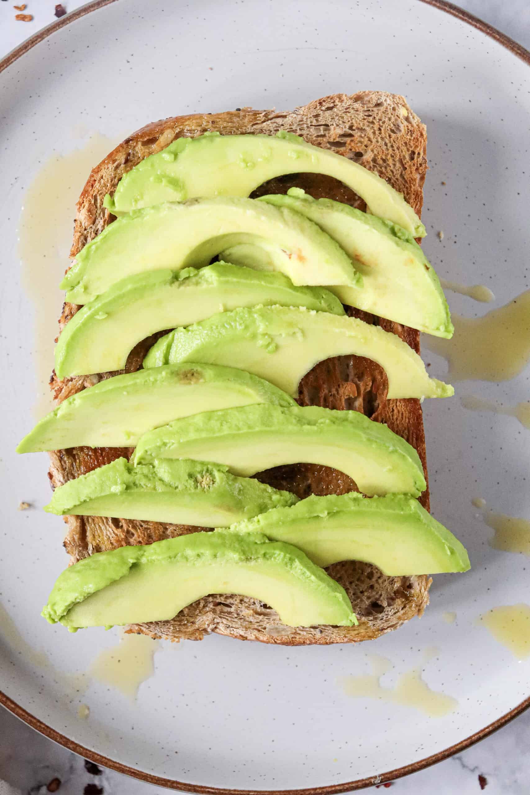 Sliced avocado arranged over golden toast.