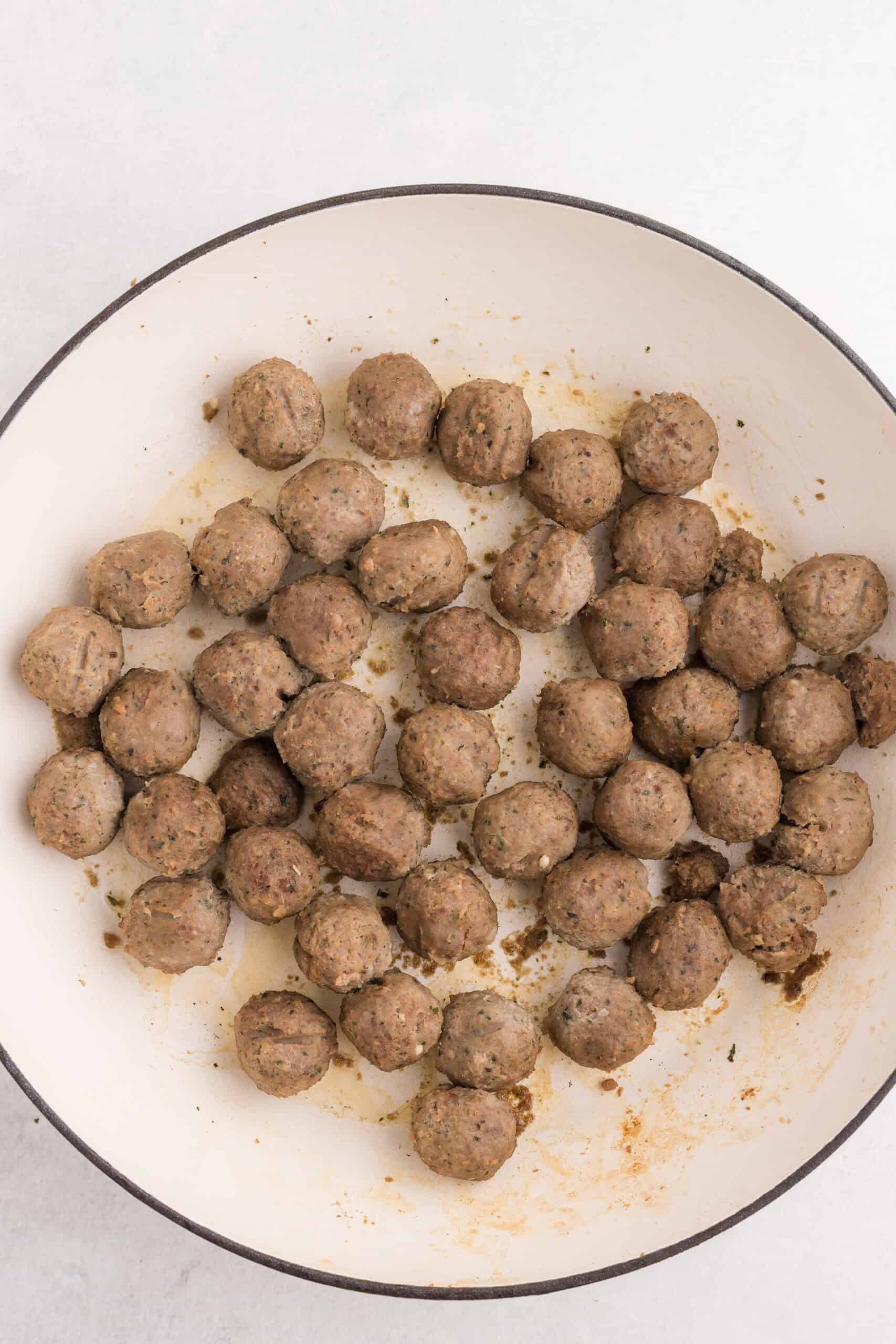 Frozen meatballs heated in a skillet.